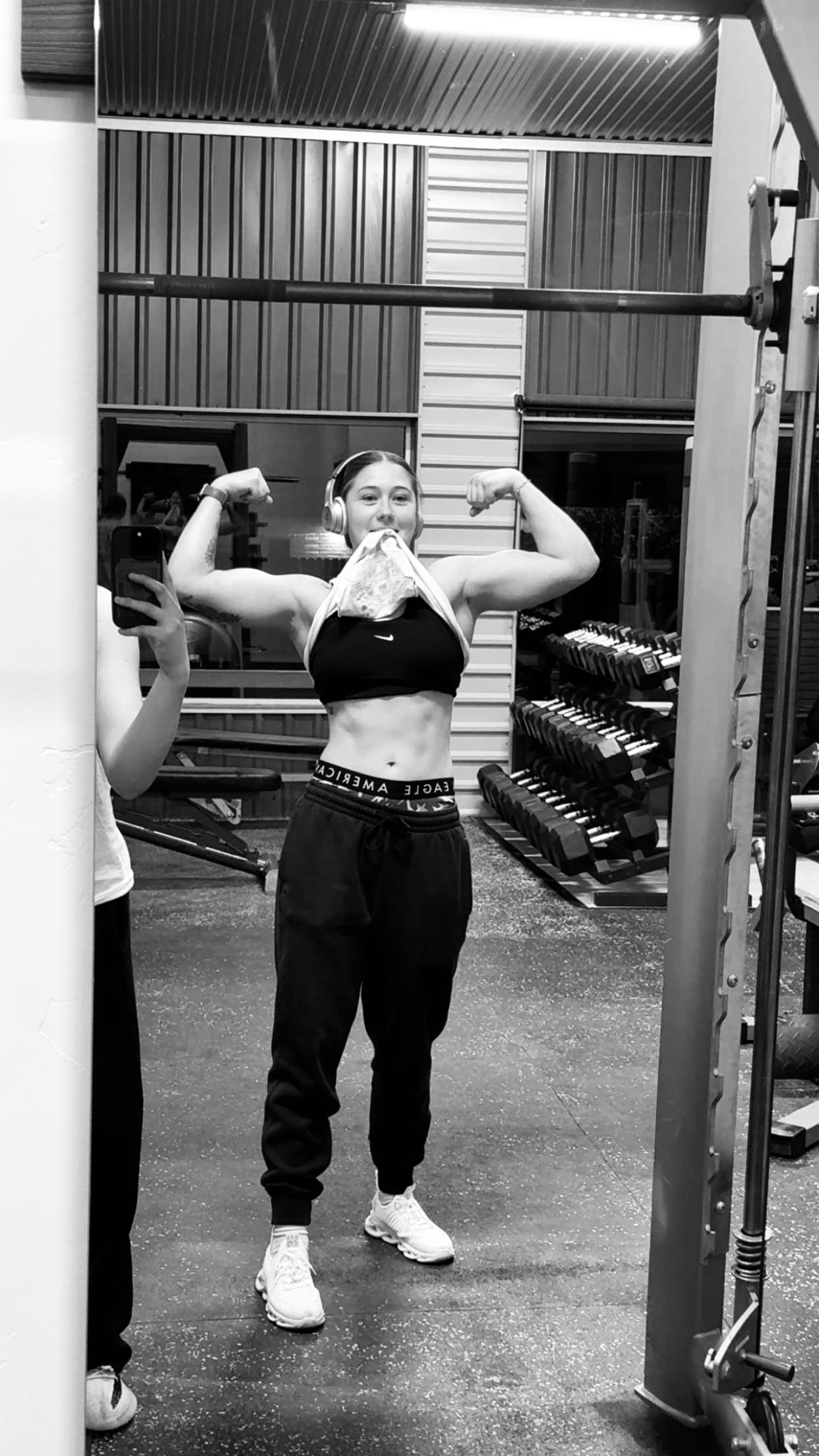 Rylee flexing both arms in the gym, in black and white