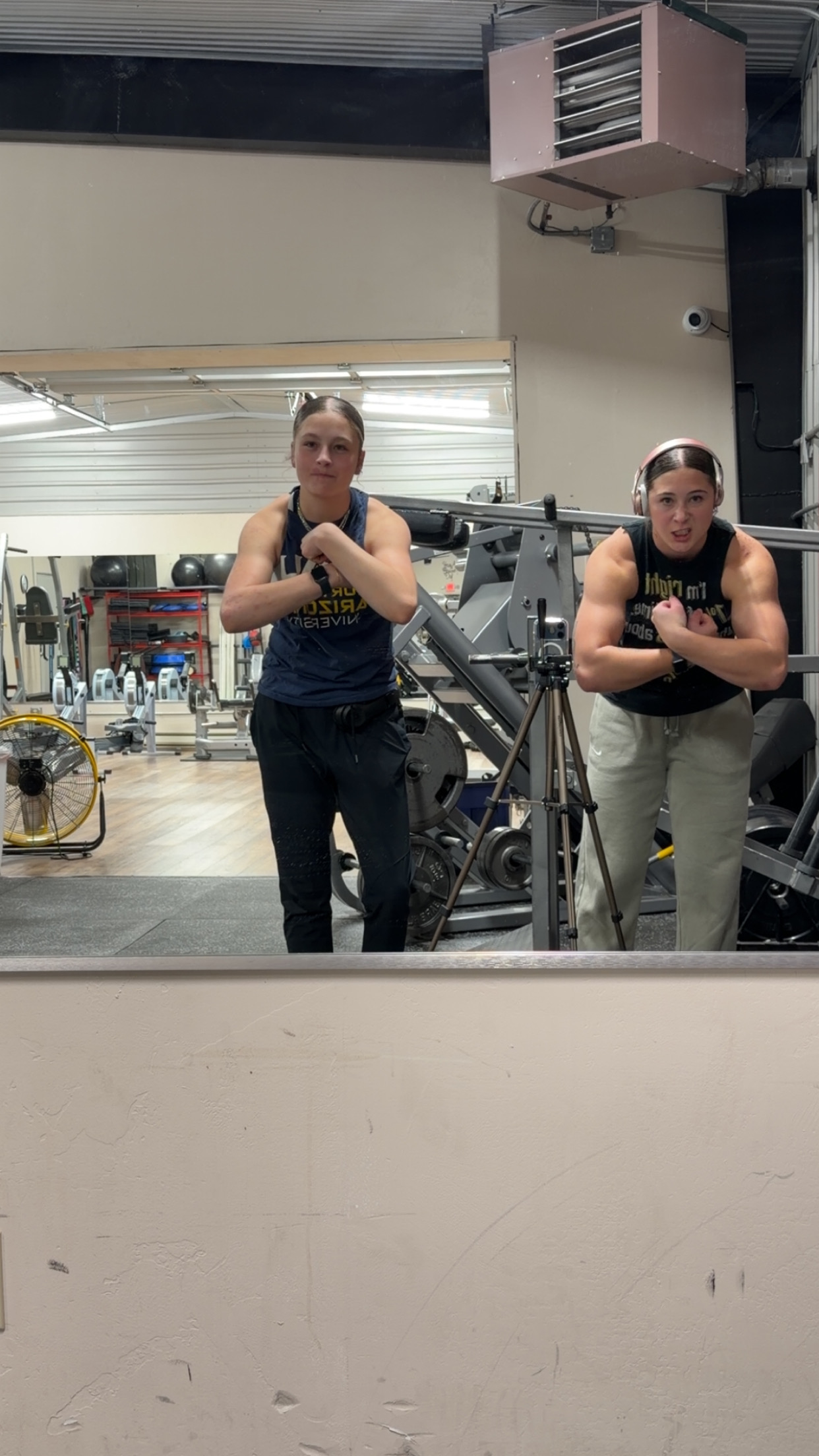 Rylee and her cousin side by side, both flexing in a gym mirror